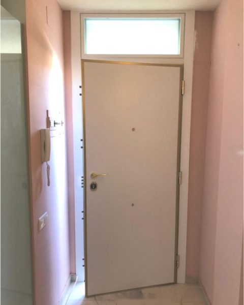 Puerta acorazada blanca con montante acristalado en un rellano