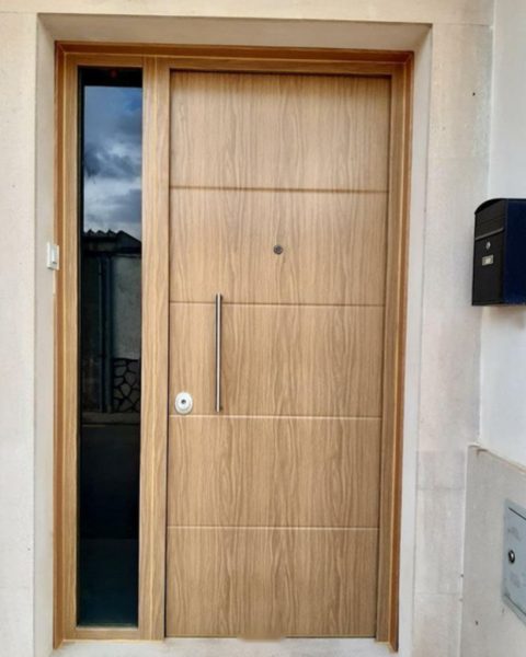 Puerta acorazada en madera con fresados horizontales y fijo lateral acristalado