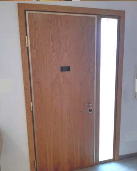 Puerta acorazada en madera con fijo lateral de vidrio translúcido