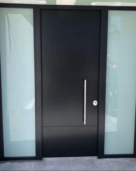 Puerta acorazada negra con tirador vertical entre dos fijos laterales de vidrio translúcido
