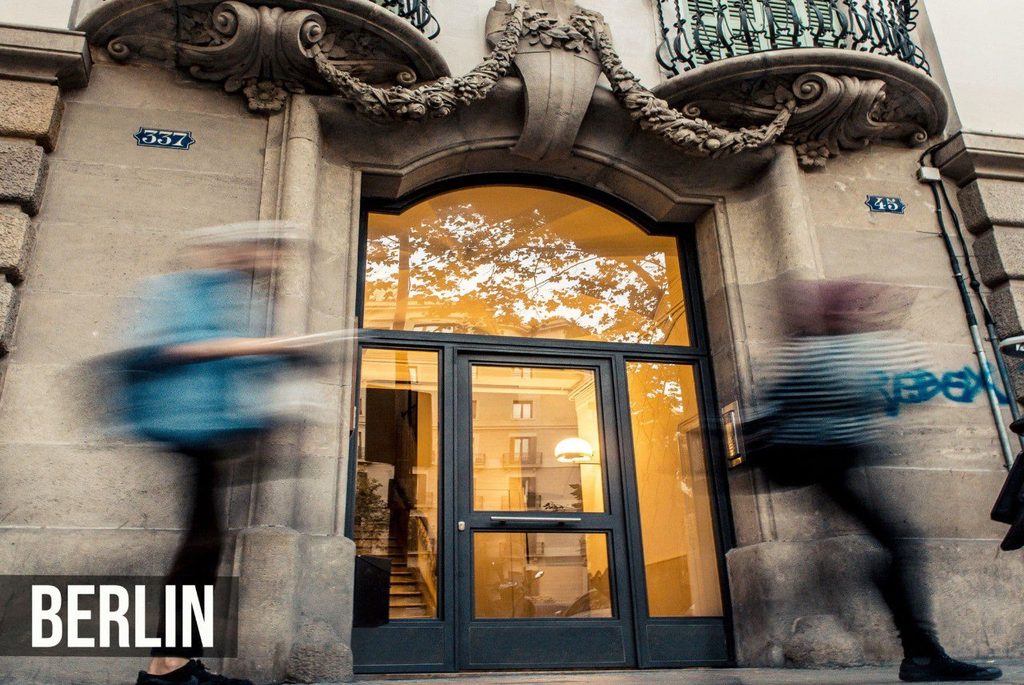 Puerta de portal modelo Berlín, de perfil fino y casi toda de vidrio, con dos hojas, fijos laterales y zócalo en la parte baja