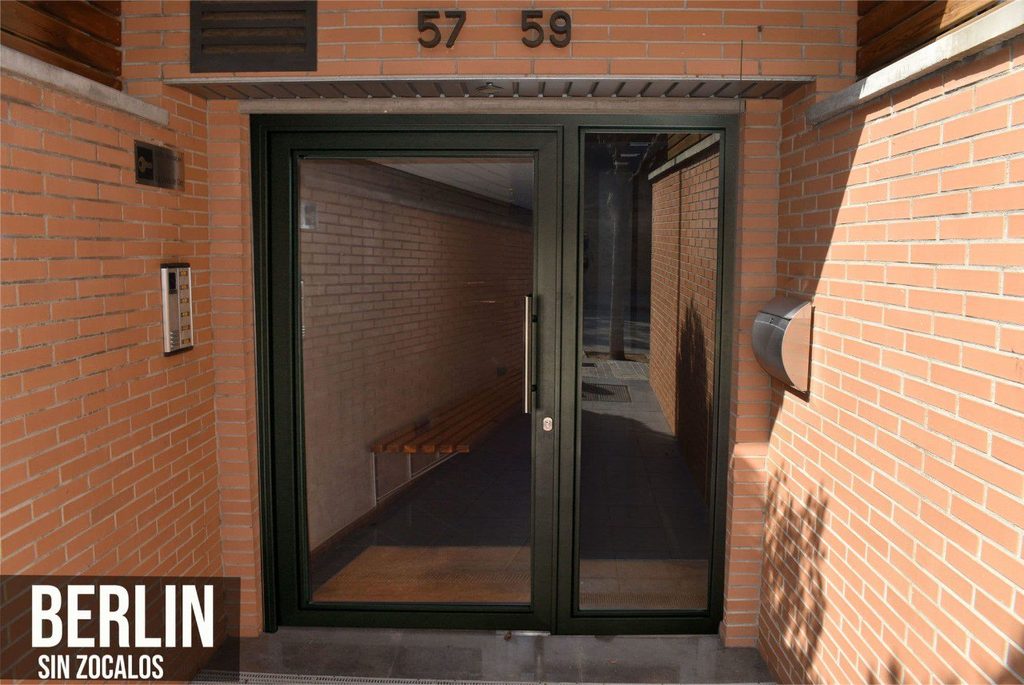 Puerta de comunidad modelo Berlín sin zócalos: hoja y fijo lateral de vidrio de arriba abajo, con perfil fino y tirador vertical