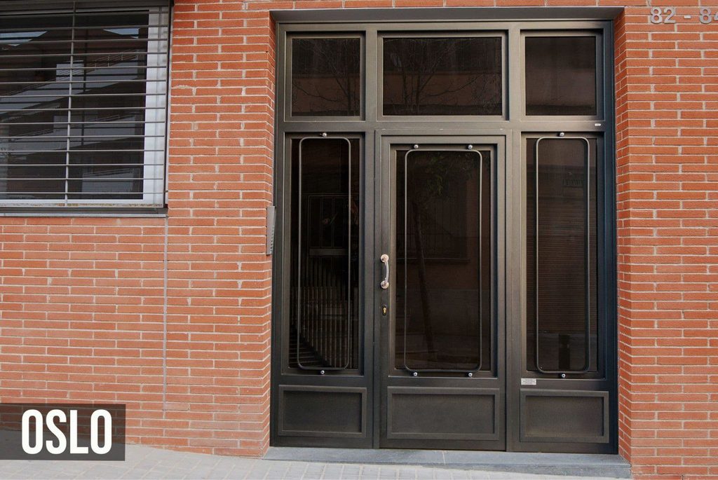Puerta de portal modelo Oslo, con óvalos rectangulares sobre el vidrio de la hoja y de los fijos laterales, zócalos abajo y montante de vidrio encima